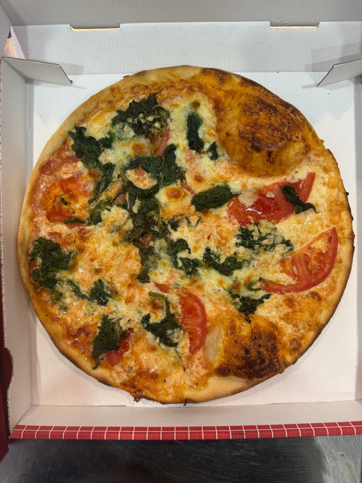 Runde Pizza mit Spinat und Tomaten